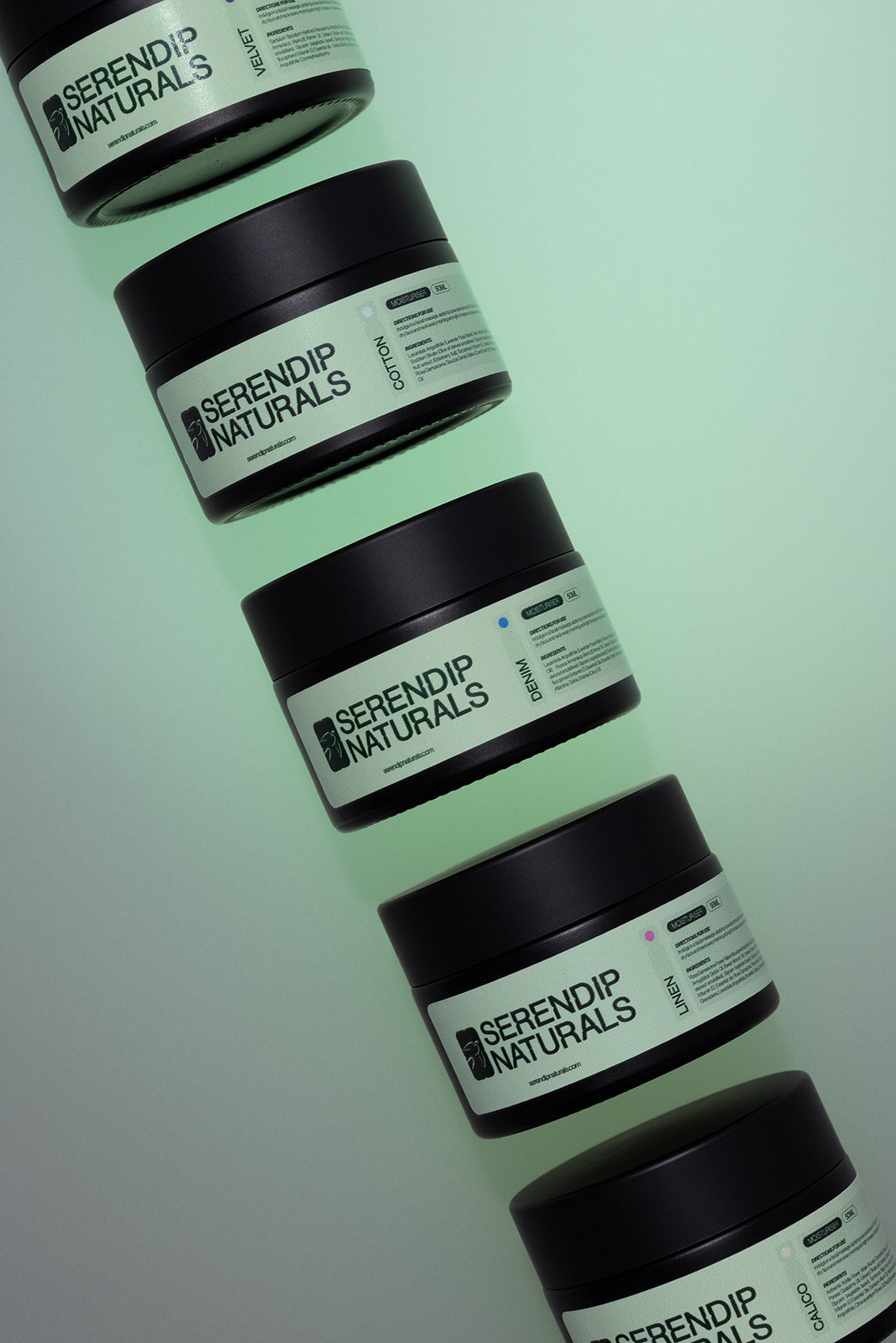 Serendip Naturals moisturiser jars arranged on a soft green background