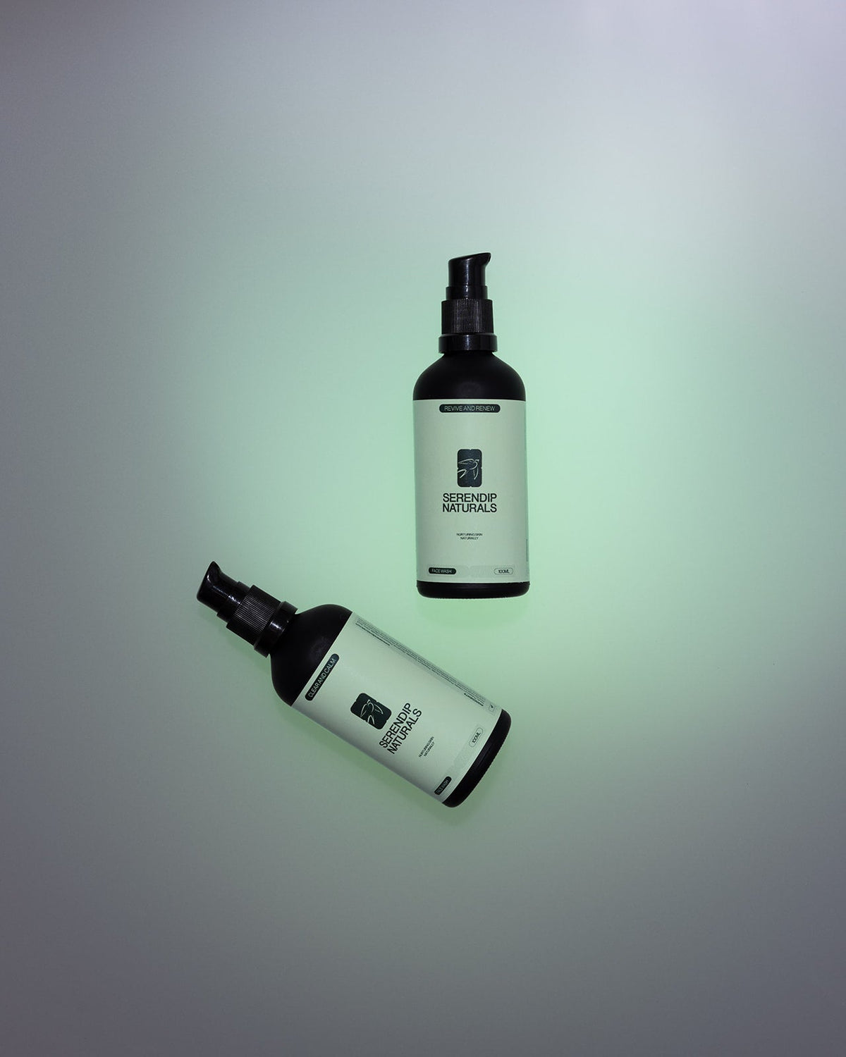 Two Serendip Naturals face wash bottles on a soft green background